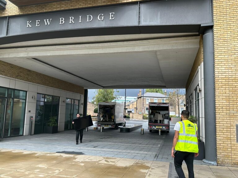 Magnus team member at the Kew Bridge building entrance with removal vans
