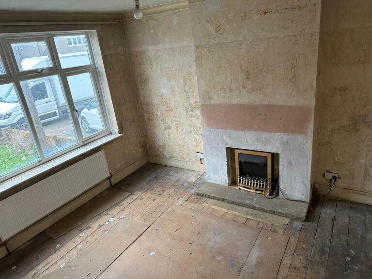 Empty living room after a clearance, with bare floorboards and a fireplace